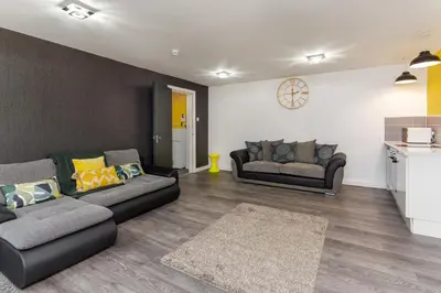 a living room with two couches and a kitchen at Snuggle Cove Apartments By Bella Vita Stays in Liverpool