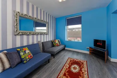a blue living room with a couch and a tv at Snuggle Cove Apartments By Bella Vita Stays in Liverpool