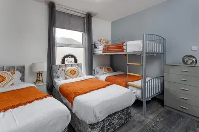 a bedroom with two beds with orange and white sheets at Snuggle Cove Apartments By Bella Vita Stays in Liverpool