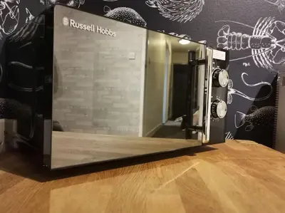 a microwave oven sitting on top of a wooden table at Lovely Centralised 1Bed Apt Near Town Centre & Beach - Free Wi-Fi & Parking in Fleetwood