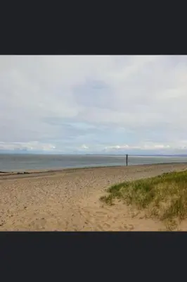 a sandy beach with the ocean in the background at Lovely Centralised 1Bed Apt Near Town Centre & Beach - Free Wi-Fi & Parking in Fleetwood