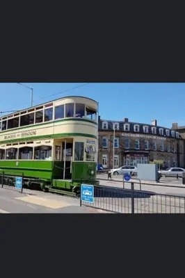 a green double decker bus on a city street at Lovely Centralised 1Bed Apt Near Town Centre & Beach - Free Wi-Fi & Parking in Fleetwood