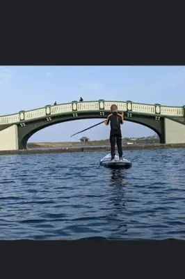a person on a paddle board in the water with a bridge at Lovely Centralised 1Bed Apt Near Town Centre & Beach - Free Wi-Fi & Parking in Fleetwood