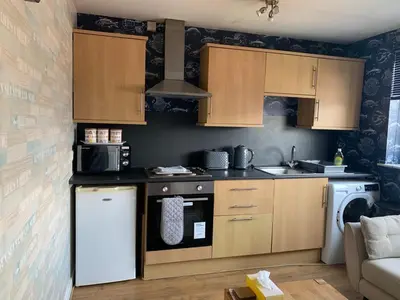 a kitchen with wooden cabinets and a white refrigerator at Lovely Centralised 1Bed Apt Near Town Centre & Beach - Free Wi-Fi & Parking in Fleetwood