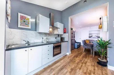 a kitchen with white cabinets and a dining room at Stunning house close to the stadium + Hot tub! in Liverpool