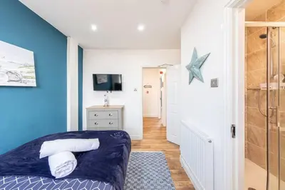 a bedroom with a blue accent wall and a bed at Stunning house close to the stadium + Hot tub! in Liverpool