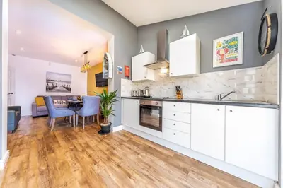 a kitchen with white cabinets and a dining room at Stunning house close to the stadium + Hot tub! in Liverpool