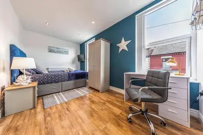 a bedroom with a bed and a desk and a chair at Stunning house close to the stadium + Hot tub! in Liverpool