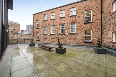 a courtyard with a bench in front of a brick building at Host & Stay - Campbell Square Roof Terrace Apartment in Liverpool