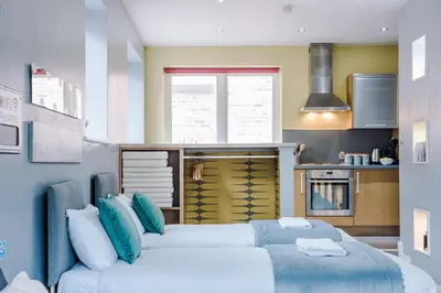 two beds in a room with a kitchen at Host & Stay - Campbell Square Roof Terrace Apartment in Liverpool