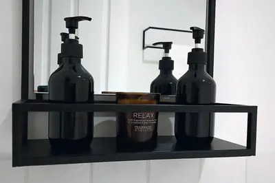 two bottles on a black shelf in front of a mirror at Stylish Apartment in City Centre with Parking in Preston