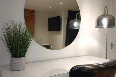 a bathroom with a mirror and a chair and a sink at Stylish Apartment in City Centre with Parking in Preston