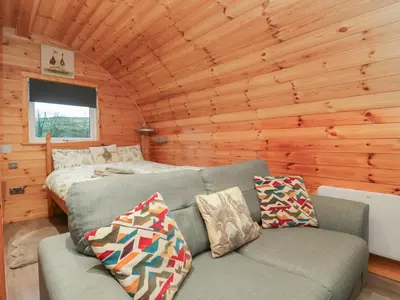 a living room with a couch and a bed in a log cabin at Rowan in Ulverston