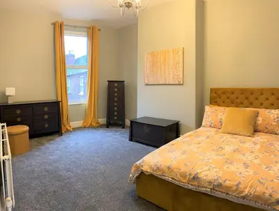 a bedroom with a bed and a dresser and a window at Beautiful Victorian Townhouse in Liverpool