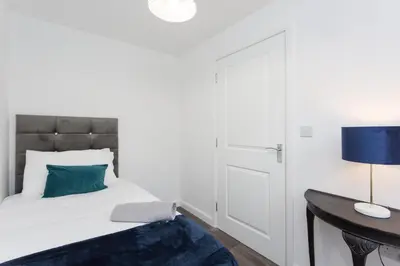 a bedroom with a bed and a table with a lamp at Main Street Town House in Leyland