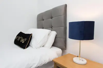 a bed with a headboard and a lamp on a table at Main Street Town House in Leyland