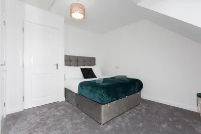 a bedroom with a bed with a green blanket at Main Street Town House in Leyland