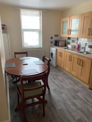 a kitchen with a table and chairs in a room at RUDGRAVE SQUARE WALLASEY in Wallasey