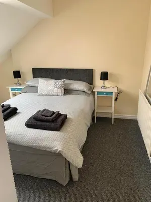 a bedroom with a bed with two tables and two lamps at RUDGRAVE SQUARE WALLASEY in Wallasey