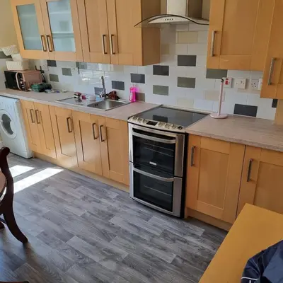 a kitchen with wooden cabinets and a sink and a stove at RUDGRAVE SQUARE WALLASEY in Wallasey