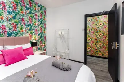 a bedroom with a large bed with pink pillows and a colorful wall at Luxury Mirror Party Pad with 4 Bedrooms! in Liverpool
