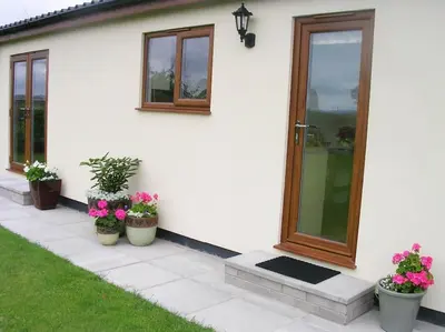 a white house with potted plants and a door at Coastal Garden Lodge in Preesall