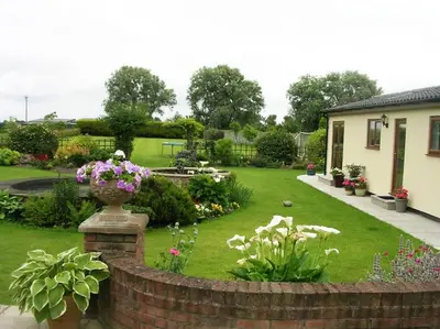 a garden with flowers and a brick fence at Coastal Garden Lodge in Preesall