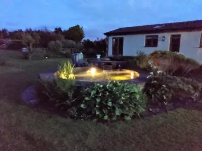 a garden with a fountain in the yard at night at Coastal Garden Lodge in Preesall