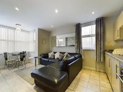 a living room with a leather couch and a table at Pearl Suite in Blackpool