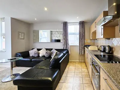 a living room with a black leather couch in a kitchen at Pearl Suite in Blackpool