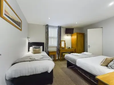 a bedroom with two beds and a desk at Pearl Suite in Blackpool