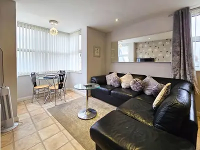 a living room with a black leather couch and a table at Pearl Suite in Blackpool