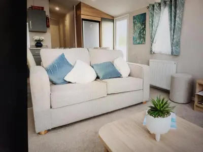 a living room with a white couch with blue pillows at 32 Bayview Oceans Edge in Morecambe