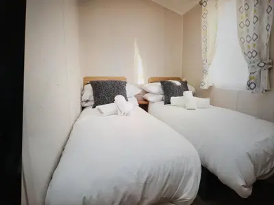 two beds in a room with white sheets and pillows at 32 Bayview Oceans Edge in Morecambe