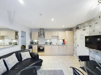 a living room with a black couch and a kitchen at Sandbanks Suite in Blackpool