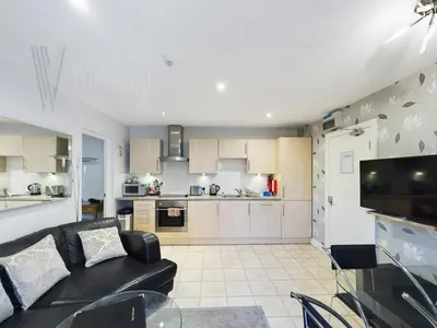 a living room with a black couch and a kitchen at Sandbanks Suite in Blackpool