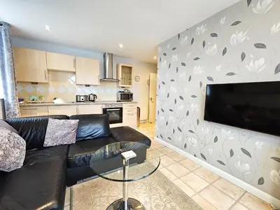 a living room with a black leather couch and a flat screen tv at Sunrise Suite in Blackpool