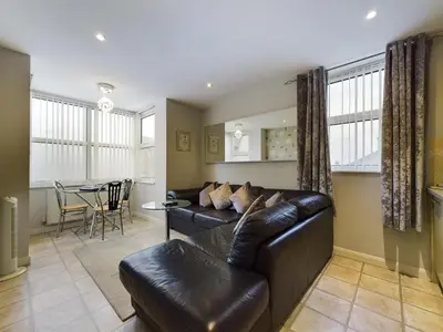a living room with a leather couch and a table at Sunrise Suite in Blackpool