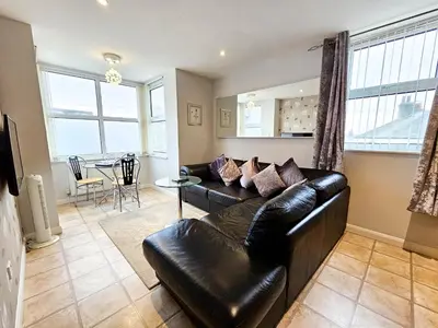 a living room with a leather couch and a table at Sunrise Suite in Blackpool