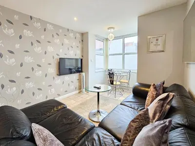 a living room with a leather couch and a tv at Sunrise Suite in Blackpool
