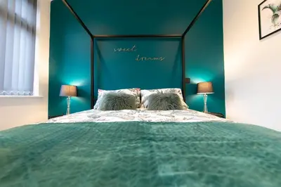 a bedroom with a large bed with a blue headboard at Stunning house near Blackpool attractions in Blackpool