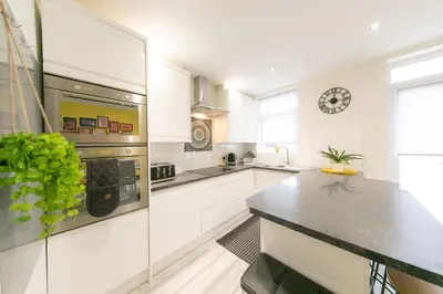 a kitchen with white cabinets and a black counter top at Stunning house near Blackpool attractions in Blackpool