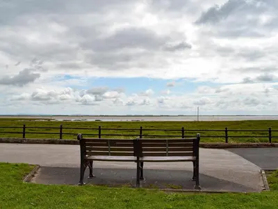 a park bench sitting on the side of a road at Honeybee Cottage in Lytham St Annes
