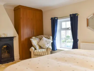 a bedroom with a bed and a chair and a window at Honeybee Cottage in Lytham St Annes