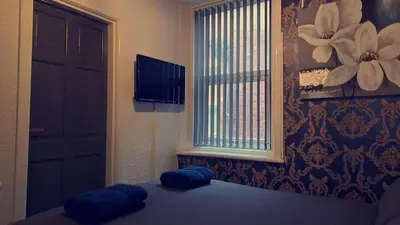 a bedroom with a bed with blue pillows and a window at Urban Inn in Blackpool