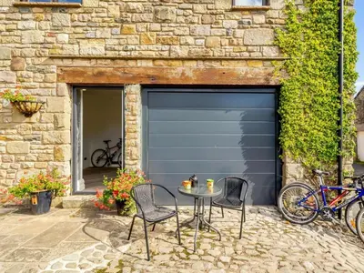 a garage door with two chairs and a table in front of it at The Artist Studio in Hest Bank