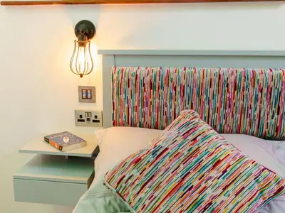 a bed with a colorful headboard with a book on it at The Artist Studio in Hest Bank