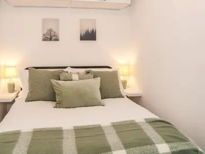 a bedroom with a green and white bed with two lamps at Hope Cottage in Hambleton