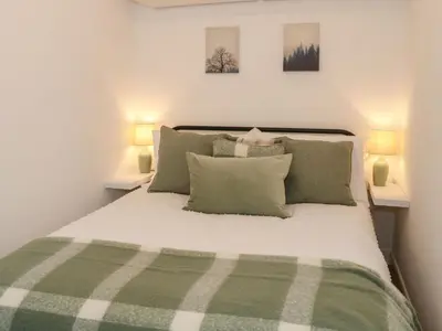 a bedroom with a green and white bed with two lamps at Hope Cottage in Hambleton