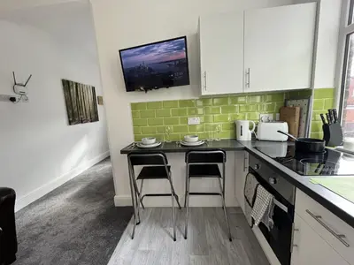 a kitchen with a counter and two bar stools at Modern 1 bed studios for comfy stay in Preston in Preston